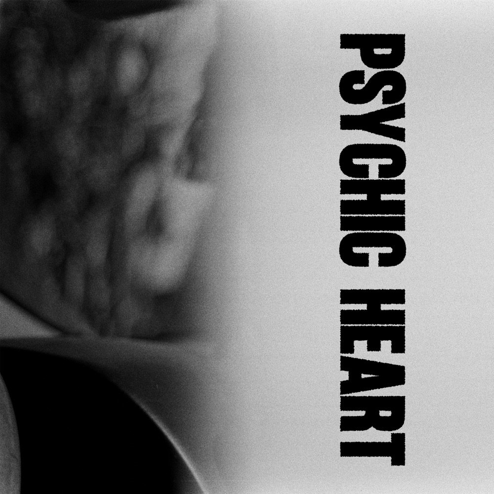 Album cover: a blurred black and white photograph with PSYCHIC HEART set in tall black letters running down the right side.
