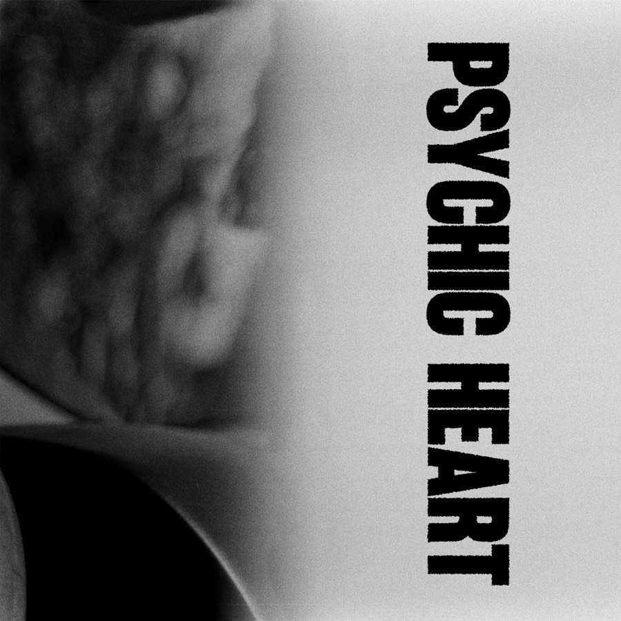Album cover: a blurred black and white photograph with PSYCHIC HEART set in tall black letters running down the right side.