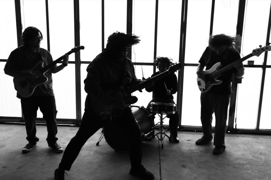 The four members of Psychic Heart playing in a room with tall windows behind them, lit from behind so they read almost as silhouettes.